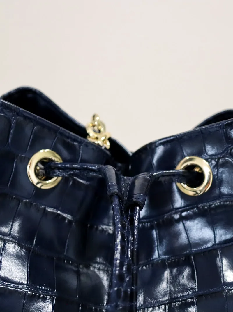 Bolso saco de piel grabada con ojales y herrajes dorados fabricado por Grupo Atelier