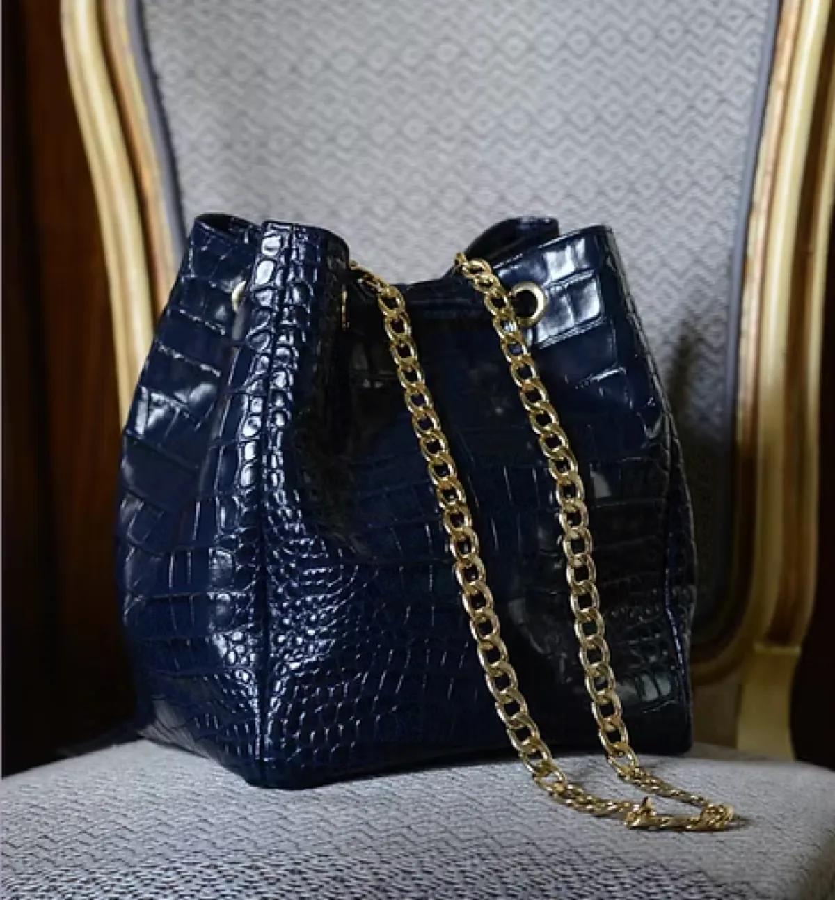 Bolso saco de piel grabada con ojales y herrajes dorados fabricado por Grupo Atelier