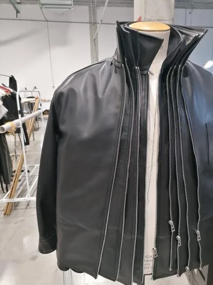 Chaqueta de piel negra con cinco cremalleras paralelas montada sobre maniquí