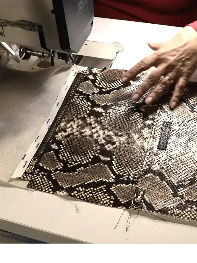 Panel de piel grabada guiado a mano bajo la máquina durante la confección